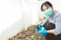 woman watering a garden wearing a mask 