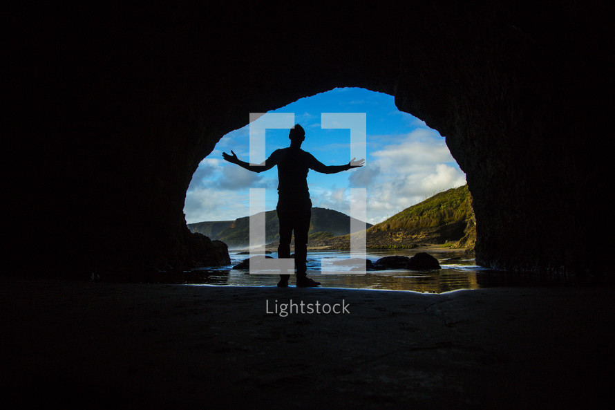 silhouette of a man in the entrance of a cave 