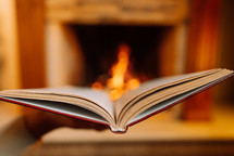 Stunning view of open book against burning fire from fireplace background. Paper literature, education concept.