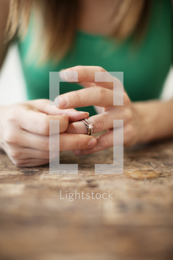 A woman taking her wedding ring off her finger. 

