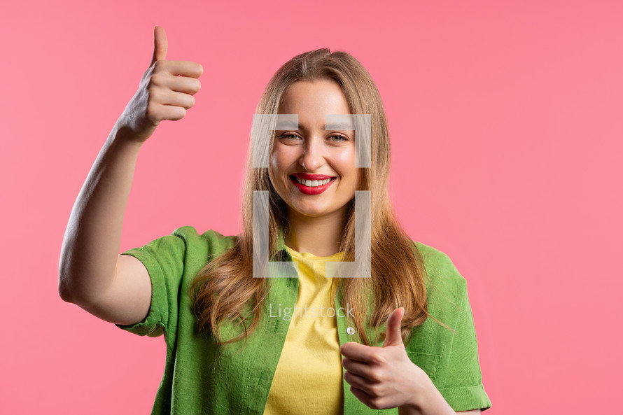 Stylish woman with hand sign like, thumbs up gesture. Happy lady, correct perfect choice, great deal, pink background. Positive female model smiles to camera, approval, trust concept.