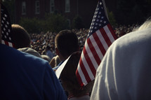 audience standing holding American flags 