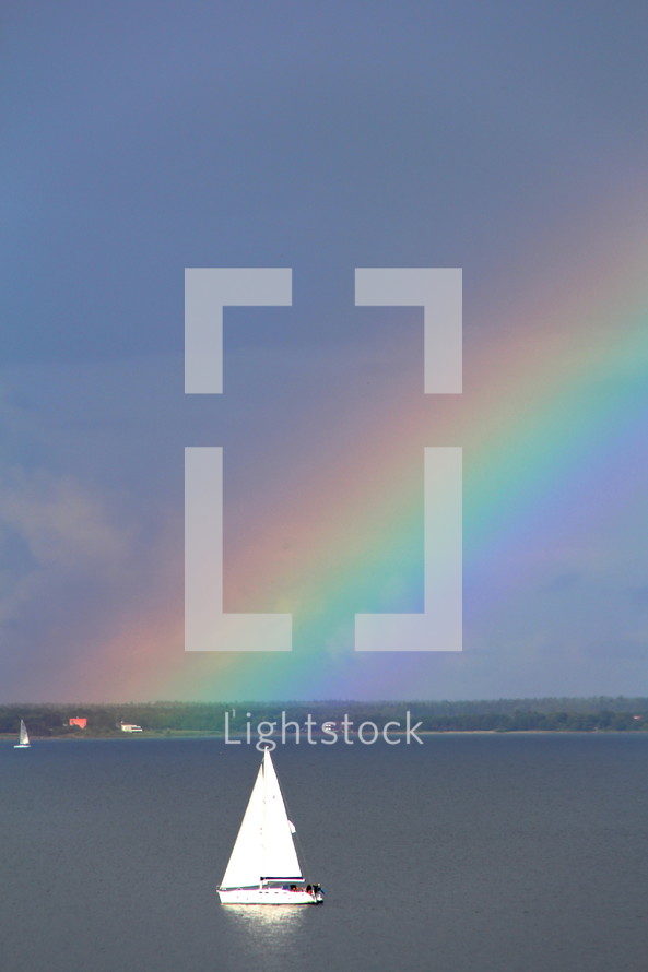 rainbow in the sky and sailboat on water 