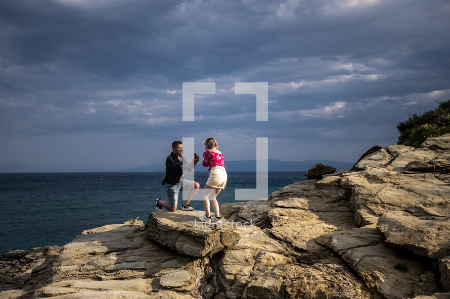 a man proposing on a rocky shore 