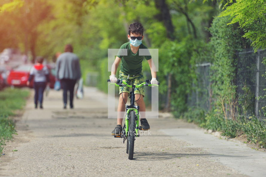 boy riding a bike on a path wearing a face mask 