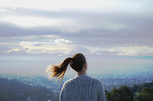 a young woman with a ponytail looking out over suburbs 