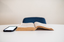 opened Bible on a table with a smartphone 