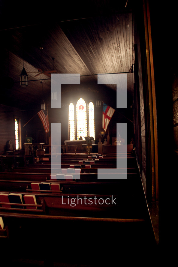 A church sanctuary with light coming through stained glass windows.