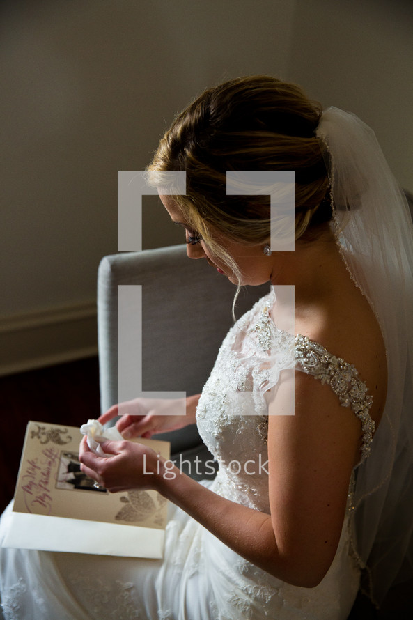 A bride holds a tissue while reading a greeting card from the groom.