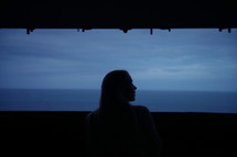 silhouette of a woman looking out at the ocean 