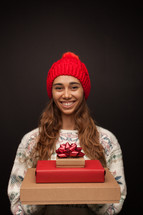 a woman holding a stack of Christmas gift boxes 