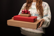 a woman holding a stack of Christmas gift boxes 