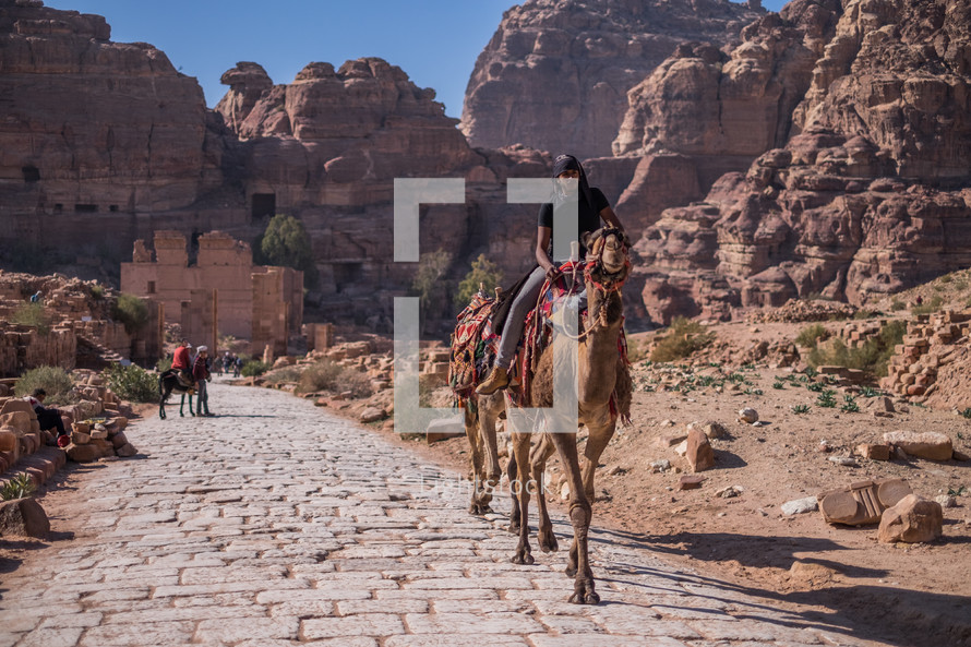 people riding on donkeys in a desert city 