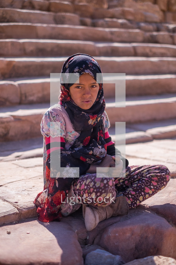 child sitting on stone steps 