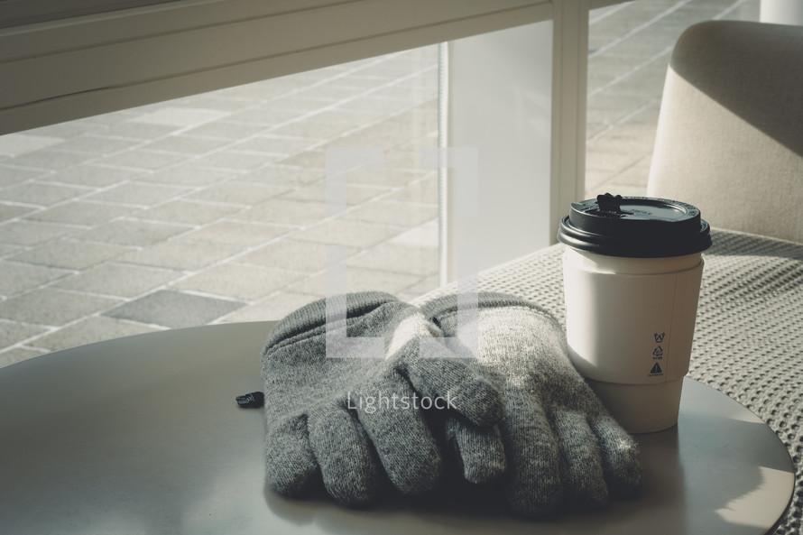 gloves on a table next to a to-go coffee cup 