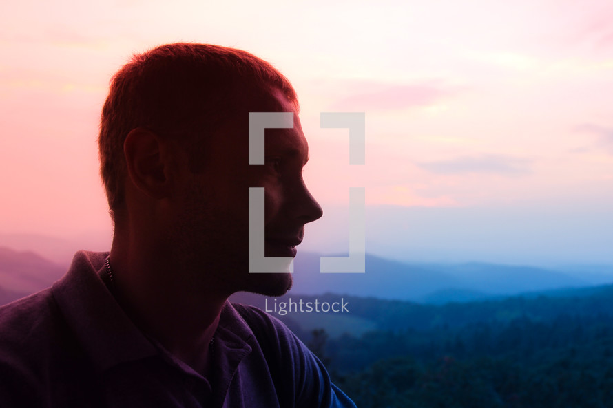 side profile of a man with mountains in the background 