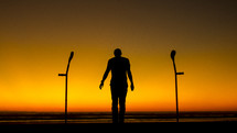 silhouette of a man standing and crutches 