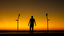 silhouette of a man standing on a beach and arm braces 