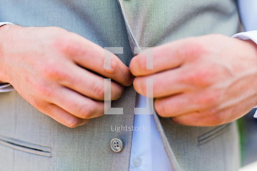 A man buttoning his suit groom wedding menswear fashion jacket 