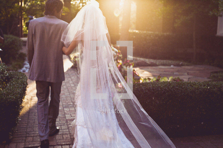 A bride and groom walking into the sun