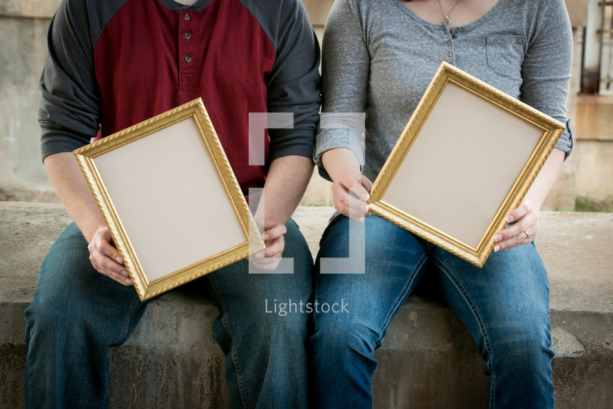 man and woman holding empty frames 