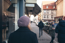 woman walking down a sidewalk near shops