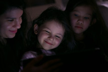 Young Mother watching a show with her children at home on in the dark