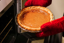 taking a pumpkin pie out of the oven 