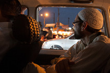 a muslim man in a prayer cap riding in the back of a car 