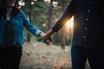 a couple walking holding hands in a forest 