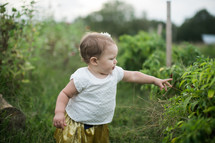 a toddler girl standing in grass