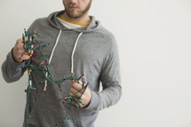 a man holding a string of tangled Christmas lights 