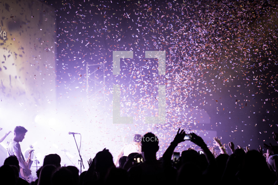 Silhouette of audience at a concert with confetti in the air.