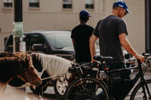 men with bicycle and ponies on a city sidewalk 
