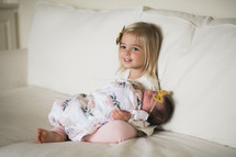 big sister holding her newborn baby sister 