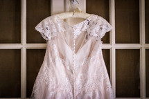 wedding gown hanging on a door 