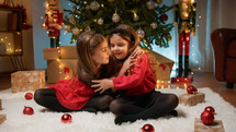 Young ladies playing and hugging under the Christmas tree 