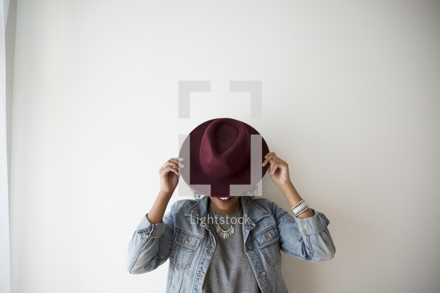 a woman covering her face with a hat 