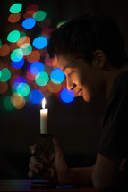colorful bokeh lights and a boy holding a candle