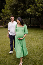 expecting couple walking in grass 