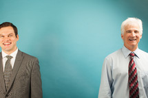two businessmen standing in front of a blue background 