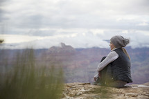 a woman sitting on a mountaintop looking out