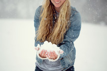 a young woman with a hand full of snow 