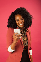 a smiling businesswoman looking at a cellphone screen 
