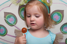 a toddler girl in a Halloween costume with a sucker 