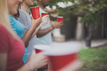 friends holding red cups at a cookout 