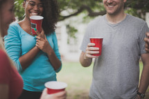 friends in conversation at a cookout holding red cups