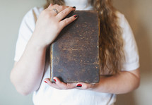 a young woman holding a well used Bible