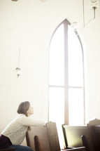 a woman looking up to God sitting in a church pew 