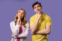 Thinking around woman and man on violet background. Smart student girl and boy couple finding answer or trying to remember what forgot, memory concept. High quality 